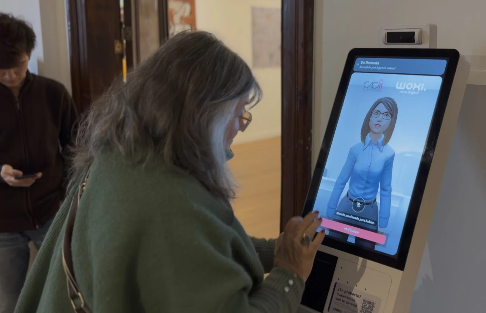 Una visitante del Centro de Arte Contemporáneo de Córdoba le hace una consulta por voz a Anto, la versión de Tina del museo, en el tótem de la sala